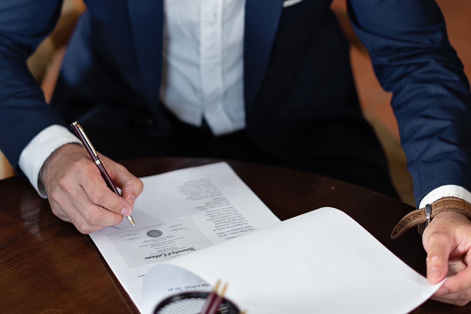 A person signing identity and business verification documents at a desk