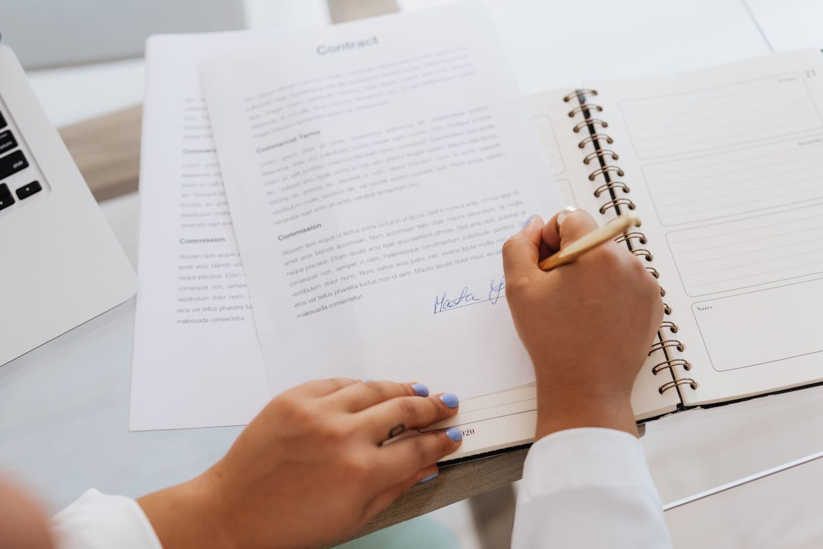 Close-up of hands signing a business authorization document at a desk.