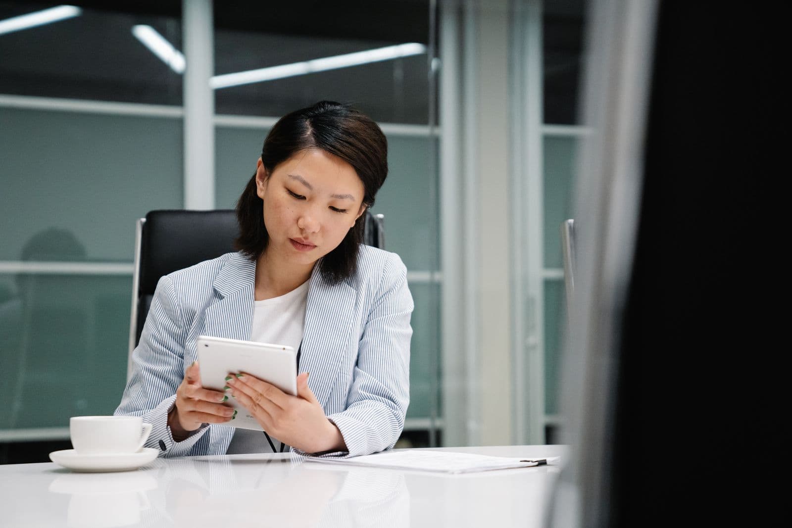 A businesswoman reviewing account data on a tablet at her desk.