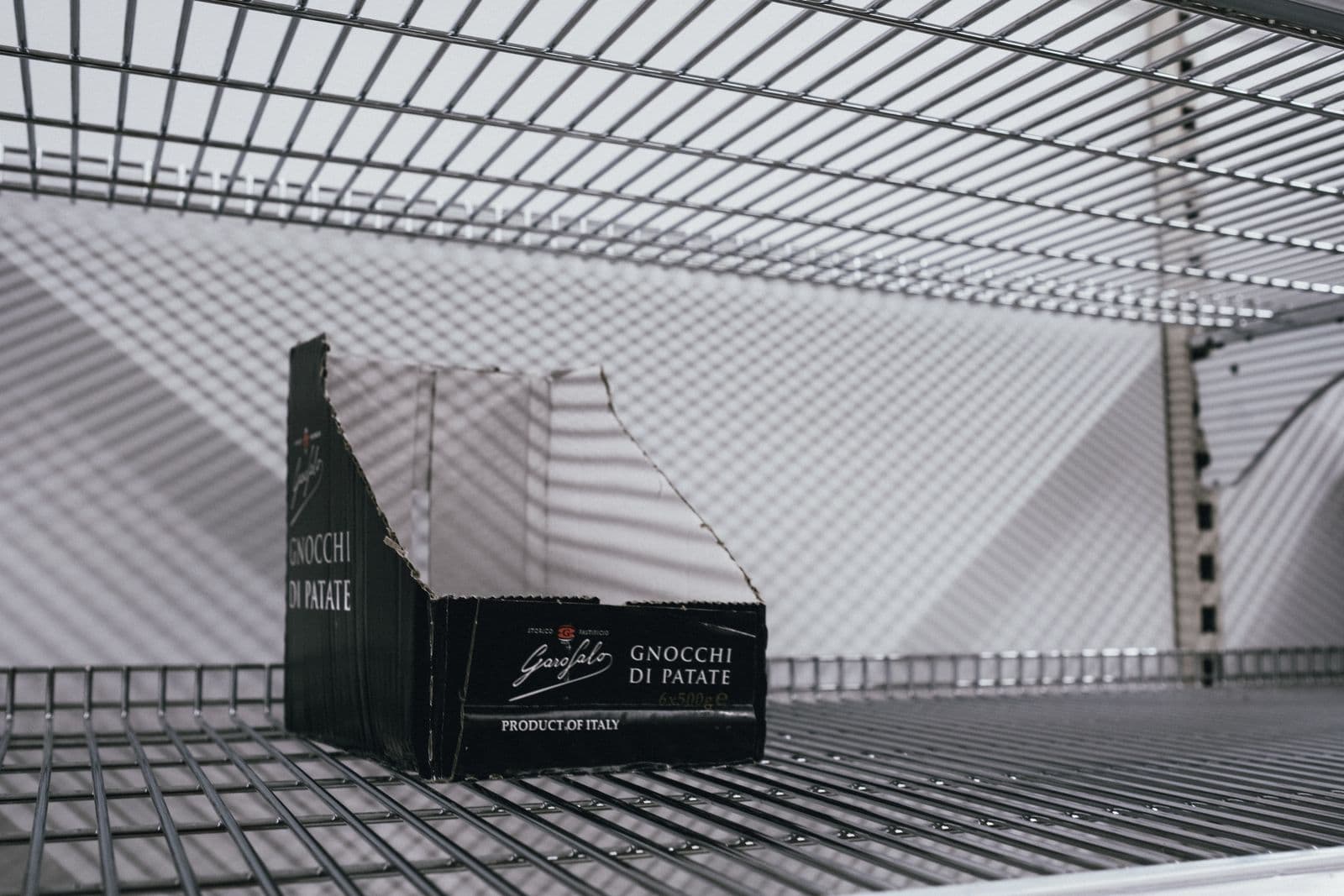 An empty supermarket shelf with a single product box left behind.