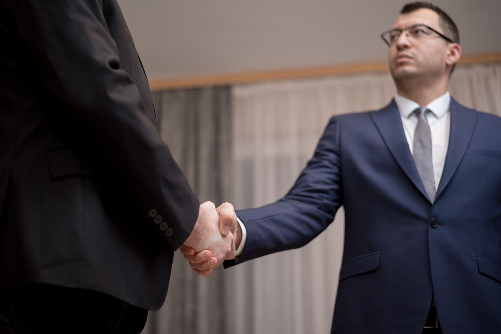 Two businessmen in suits shaking hands to seal an agreement.
