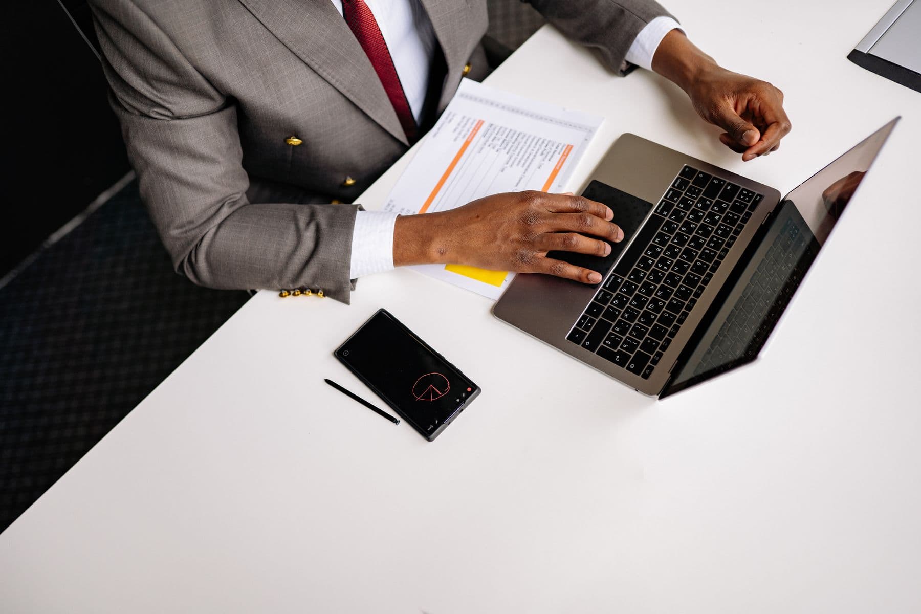 A professional in business attire working at a laptop in an office, preparing documents for submission.