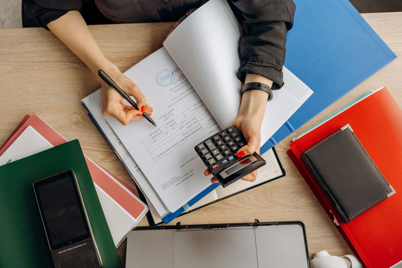 An accountant reviewing financial documents and using a calculator at a desk.